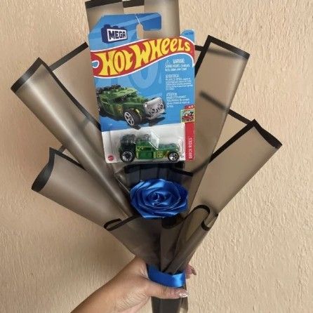Ramo con un carrito Hot Wheels verde y una rosa azul en papel negro