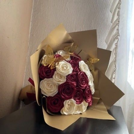 Ramo de 24 rosas vino y blancas con mariposas doradas, envuelto en papel dorado